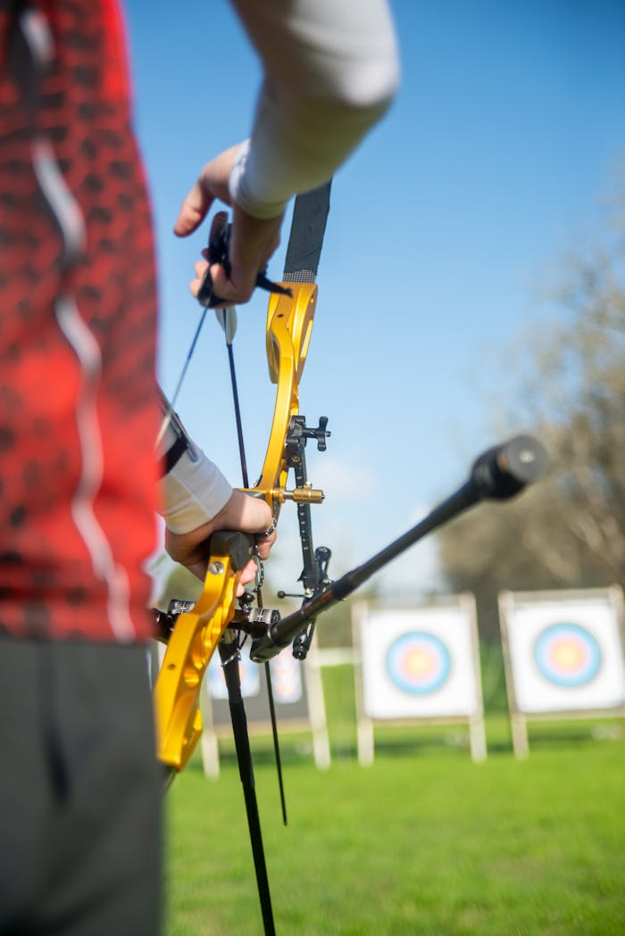 An archer focuses on hitting the target during a sunny outdoor session.